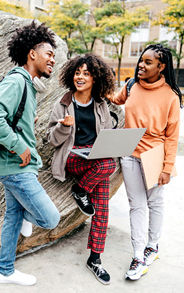 three young people standing outside talking