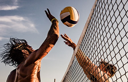 closeup of two men hitting volleyball over net